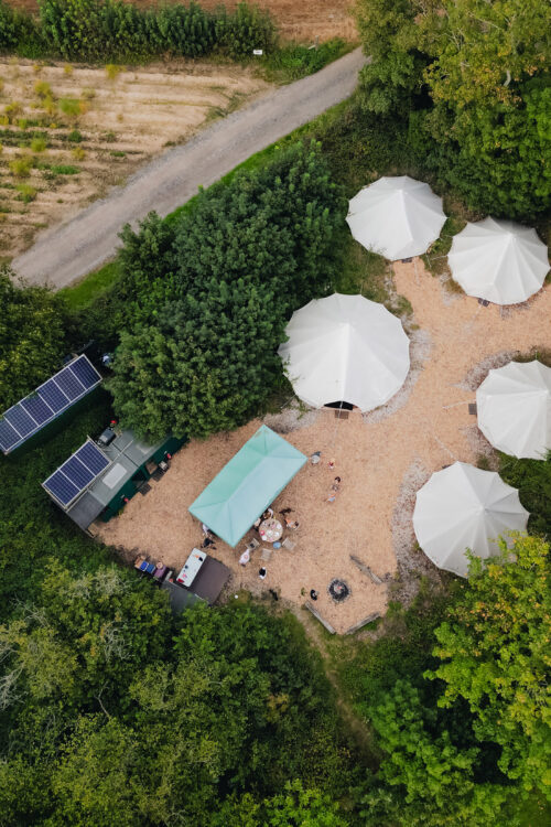 Aerial view of six white tents and solar panels.
