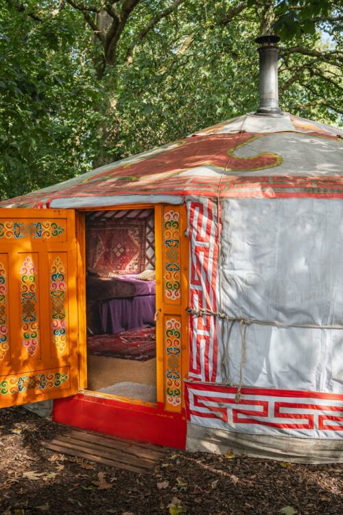 White yurt with a large orange door.
