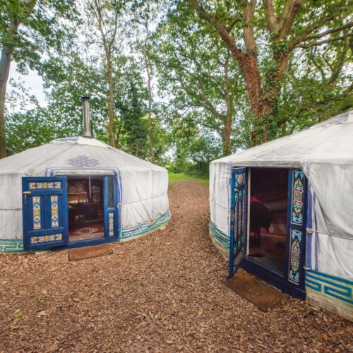 Two white yurts with open blue doors.