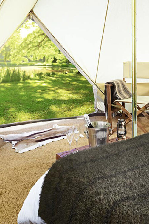 Safari bell tent decorated with a large double bed and two chairs.